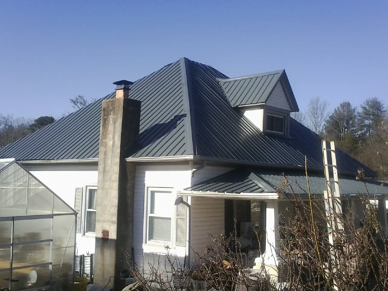 Dark blue standing seam metal roof on a white farmhouse with dormer — Slate & Tile Roof Repair by Roofing Brothers in Seffner
