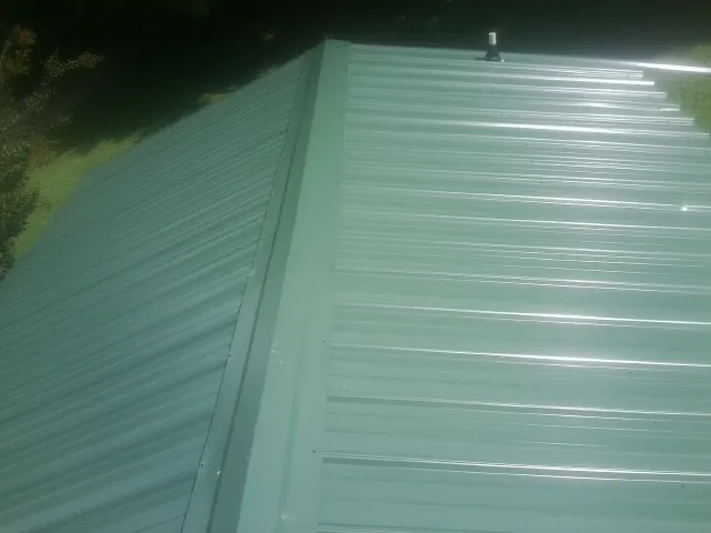 New green metal panels meeting at the ridge of a roof — Flat Roof Repair work by our crew in Seffner