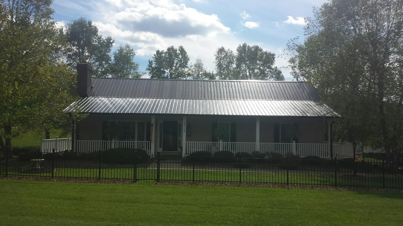 Gray metal roof on a brick ranch with a full width front porch — Gutter Guard Installation work by our crew in Seffner