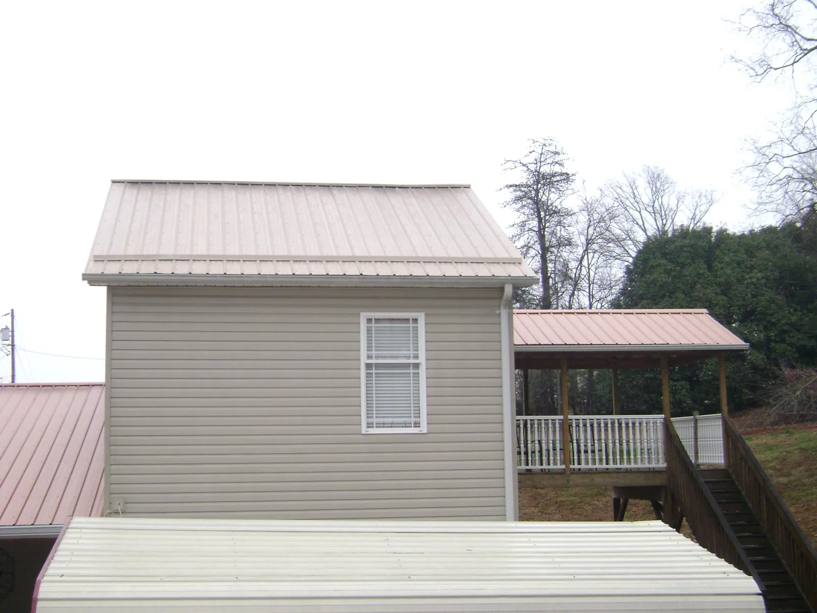 Tan metal roofs on a two story addition and attached porch, from a Roof Replacement job in Seffner