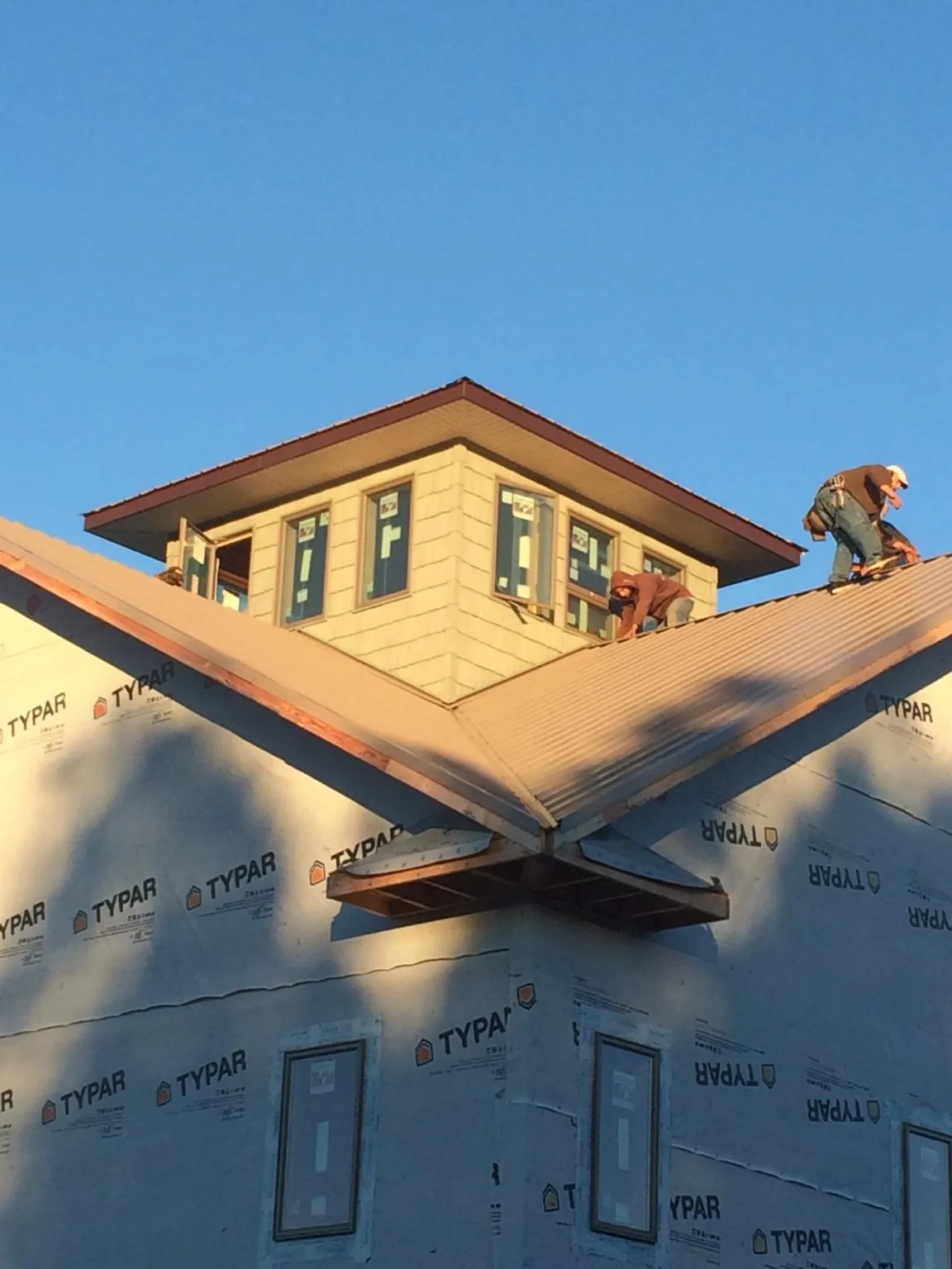 Roofers working around a rooftop cupola on a new metal roof at sunset — Roof Waterproofing in Seffner by Roofing Brothers